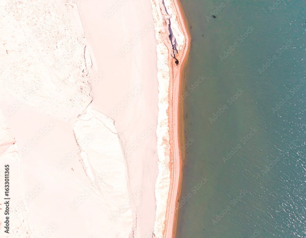 Fototapeta premium Summer seascape beautiful waves, blue sea water in sunny day. Top view from drone. Sea aerial view, amazing tropical nature background. Beautiful bright sea with waves splashing and beach sand concept
