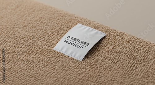 White clothing label mockup with custom text on a gray textured fabric background for branding presentation.