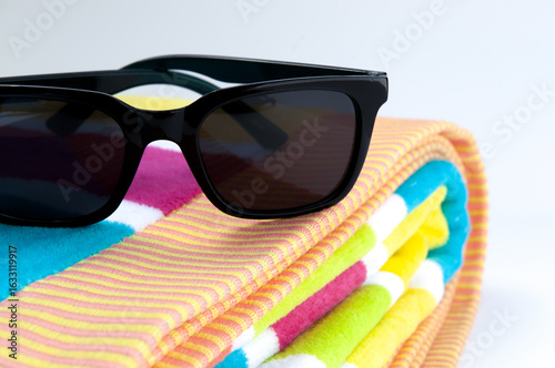 black Wayfarer sun glasses and neon striped beach towel