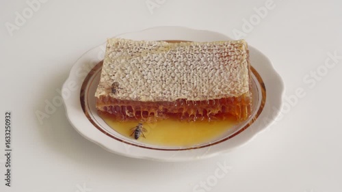 Honeybees Crawling on Honeycomb with Honey Spill on a Plate.