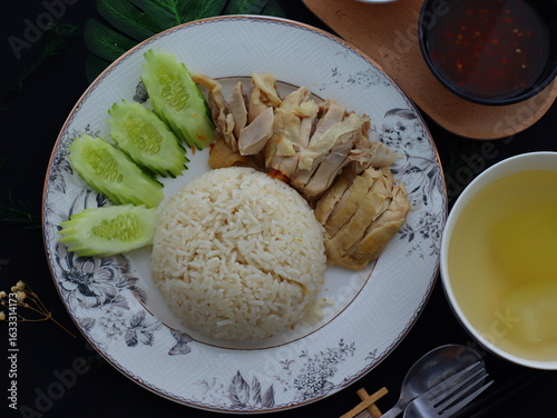 Khao Man Gai — Thai-style Hainanese chicken rice featuring tender boiled chicken served with aromatic chicken oil rice, rich soy-based dipping sauce, and fresh cucumber slices. A beloved Thai comfort 