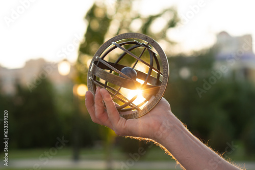Foto Extended arm holding antique globe illuminated by sunset rays
