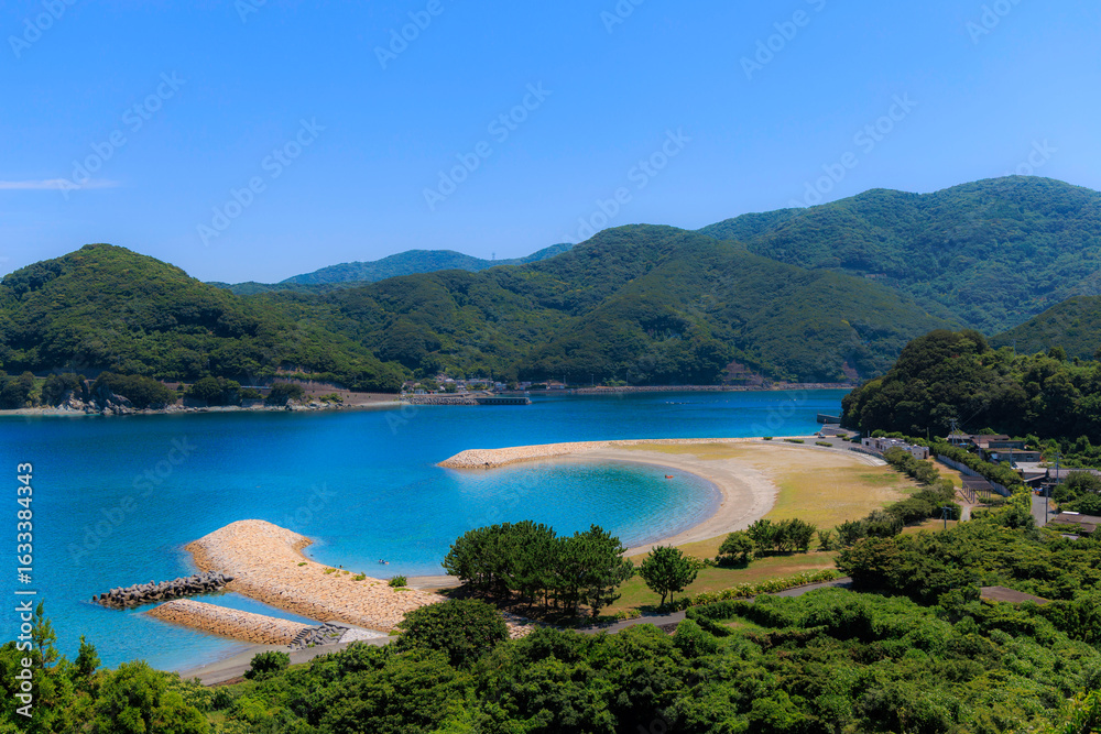 Fototapeta premium 澄んだ青い海と緑の山が広がるムーンビーチ井野浦の絶景風景