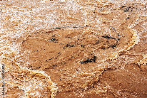 Smudged water flows profusely. River water flowing profusely. Flood waters rushing down river after storm flows through. Turbulent river dam. Water turbulence of river due to dam. Water Nature Texture