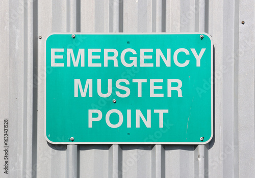 Emergency Muster Point safety sign attached to a metal corrugated wall