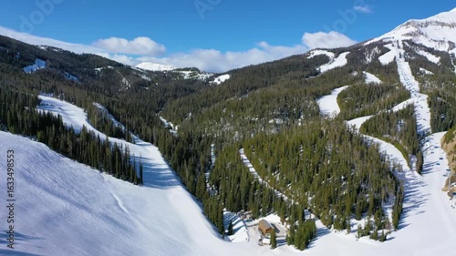 Wallpaper Mural Aerial footage of Big Sky’s ski resort in winter shows chair lifts full of skiers, with powdery slopes, pine-lined runs, and frozen peaks all around in this breathtaking mountain setting. Torontodigital.ca