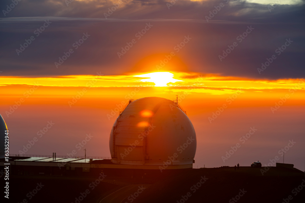 Obraz premium Astronomical observatories atop Mauna Kea, Hawaii, stand above the clouds at sunset, capturing a breathtaking view from one of the world’s premier stargazing locations.