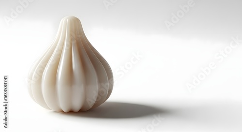 Close up shot of a single modak sweet on a white surface with a soft shadow cast to the right side