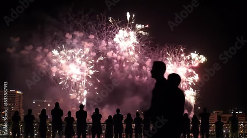 Silhouettes of Crowd Watching Spectacular Fireworks Display Over City at Night