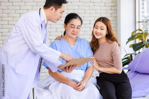 Asian man professional doctor visiting ward talking giving report good news to smiling and happy family and senior woman patient sitting on hospital bed with lovely daughter showing healthcare support