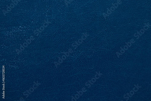 Dark blue faux leather background with cracks and folds texture, close-up of material for upholstery, design