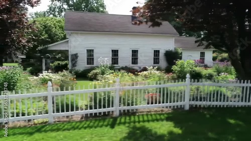 Picturesque exterior view of a house with a beautiful garden and white fence