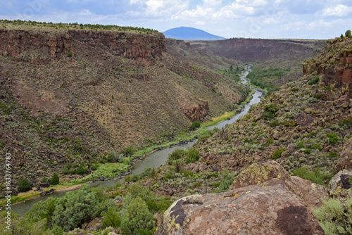 looking  out at  mountains  and  the  rio grande river from  a steep overlook in the rio grande del norte national monument  near taos, new mexico, on a  summer day 