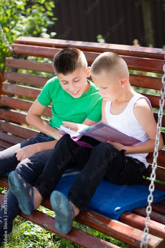 Fototapeta premium Brothers share a storybook moment on a swinging bench, bathed in sunlight. Connection, exploration, and summer vibes. 127 characters