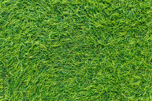 A close-up view of vibrant green artificial grass blades, creating a lush, textured surface.