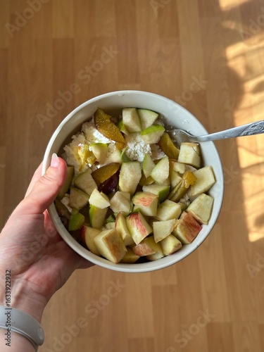 Top view of hands holding plate with cottage cheese and apple slices