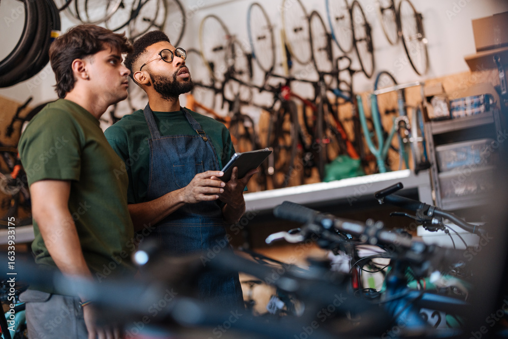 Obraz premium Bicycle mechanics using digital tablet discussing a repair in their workshop