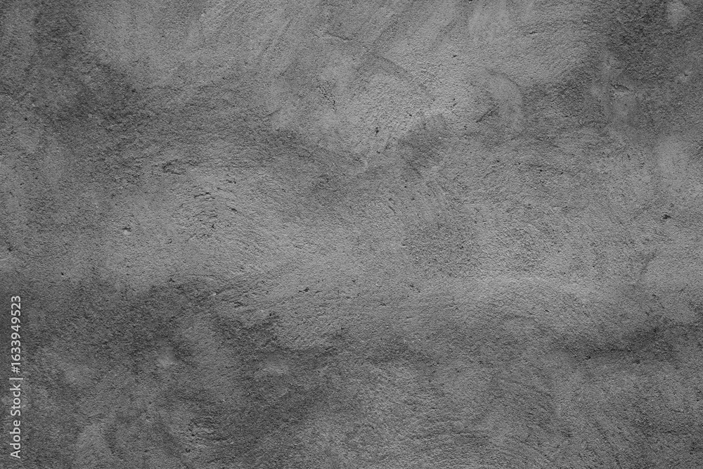 Naklejka premium This is a grayscale image showing a textured surface that resembles a concrete wall or a similar rough, uneven material. The tones range from light to dark gray, creating a subtle, mottled pattern.