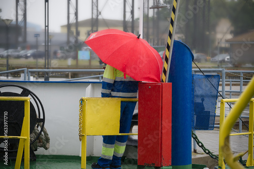 Person Holding Red Umbrella While Onboard a Ship During Rainy Weather