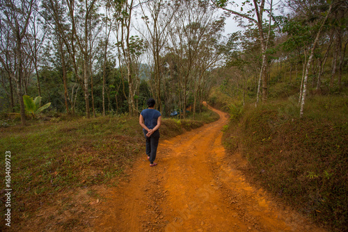 A lady walking along a dusty trail in a village in Kerala