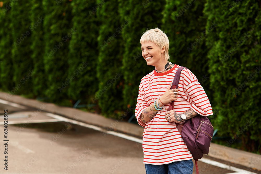 Fototapeta premium Stylish young woman enjoying a sunny day in the park with vibrant greenery around