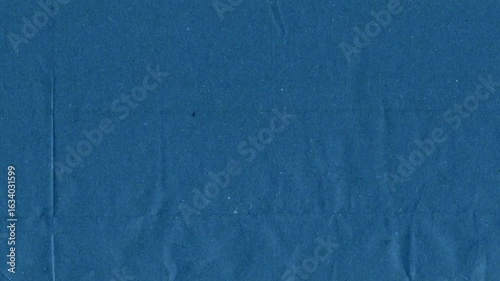 Blue kraft paper noise texture 4K stop motion video. Aged old page overlay effect background loop animation. Vintage paper texture with crease, stain, grain, dust particles. Empty animated backdrop