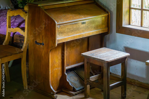 Foto Antique harmonium with closed lid and air pedals, standing by the window in a traditional interior