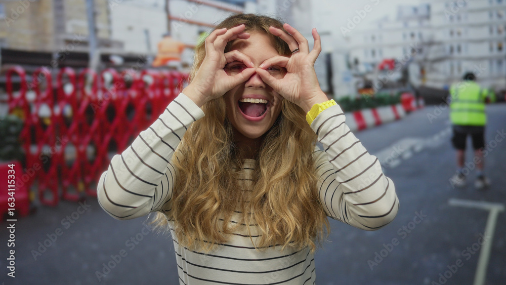 Fototapeta premium Woman hair peeking street captures blonde young model at construction barricade in city happy pose.