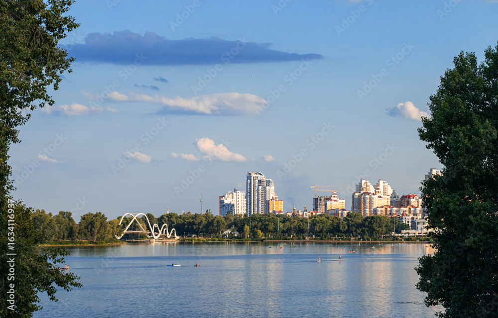 Naklejka premium city skyline panorama summer clear weather day view river and natural frame foreground with skyscrapers and bridge across river Ukraine capital Kyiv