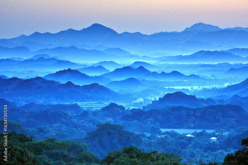 Fototapeta premium Misty mountain range panorama in soft blue tones