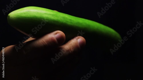 Man swowcasing organic cucumber in his hand. Healthy vegetarian diet