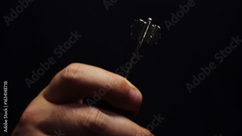 Man holding a key from some massive door twisting it in the dim lights, isolated dark background