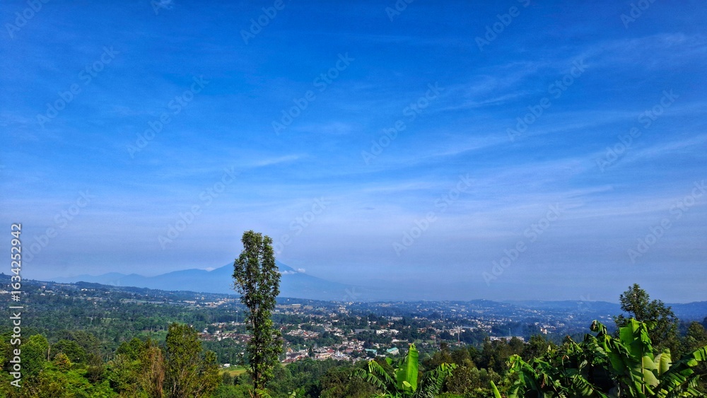 Fototapeta premium Mountains landscape. Panorama of beautiful countryside of Indonesia in sunny afternoon. landscape in mountains. grassy field and rolling hills. rural scenery with blue sky.