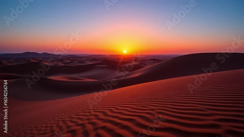 Golden sun dips below desert horizon casting warm light on rolling sand dunes at sunset