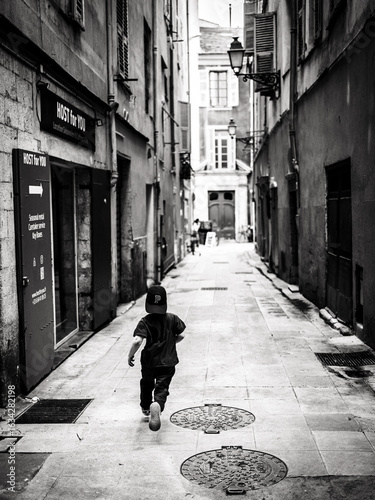 Curious Child Wanderer Exploring Quaint Narrow Parisian Alleyway in Urban Black and White Setting