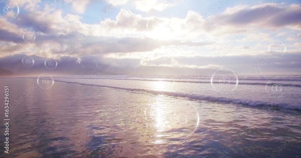 Obraz premium Casting golden sunlight across water at ocean shoreline, with translucent circular digital overlays