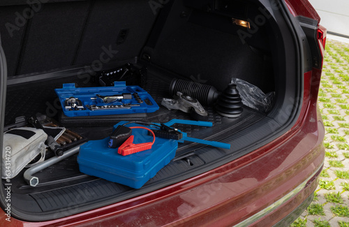 Trunk of car with automotive tools including wrench set and jumper cables