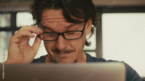 Man Removing Glasses Due to Eye Strain from Laptop