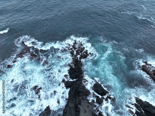 Aerial View of a Wave Crashing Against Volcanic Coastline

