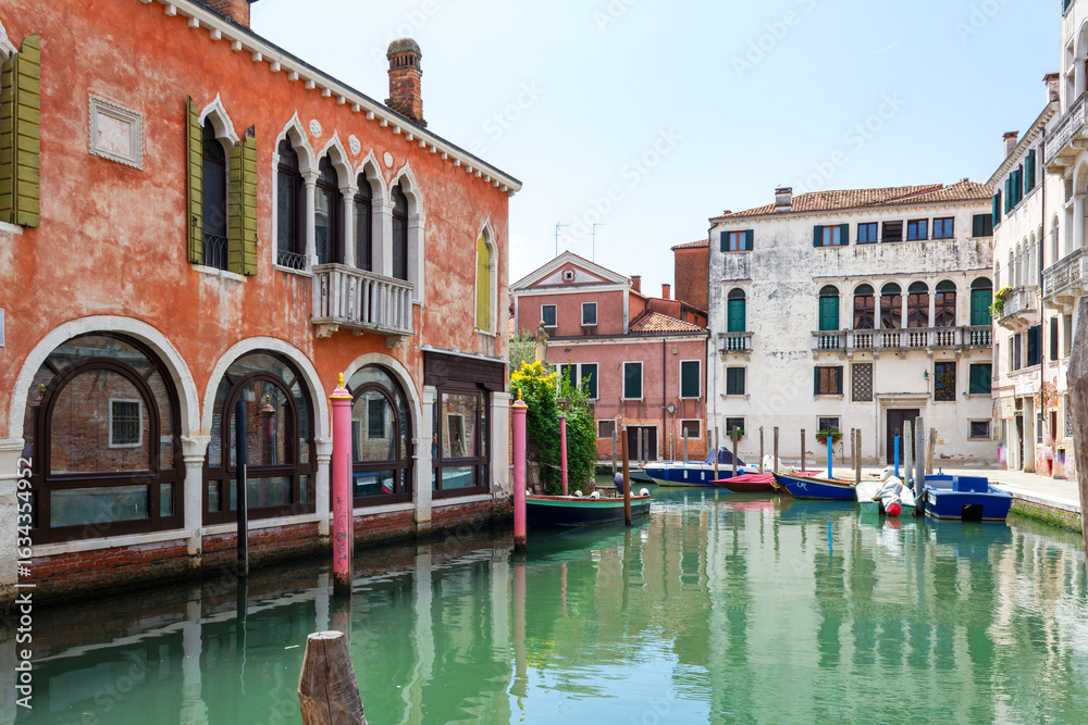 Obraz premium View of the unique and characteristic Venetian canals, where typical boats knew as Gondola are used for tourist sightseeing. Worldwide famous, Venezia is a unique kind of city and UNESCO site.