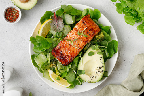Baked roasted salmon steak with green healthy salad with avocado. Fresh diet dinner meal. Vitamin food concept on the plate and grey background.