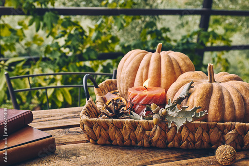 Cozy warm autumn composition with burning candle and pumpkins on knitted woolen plaid. Autumn home decor. Fall mood. Thanksgiving. Halloween.