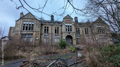 Derelict Old Batley General Hospital and District Cottage Medical Centre. Abandoned country mansion grounds in disrepair. Boarded up, imposing, creepy, empty haunted building viewed through branches.