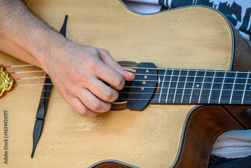 Photography A guitarist picking the strings of a gypsy jazz style guitar