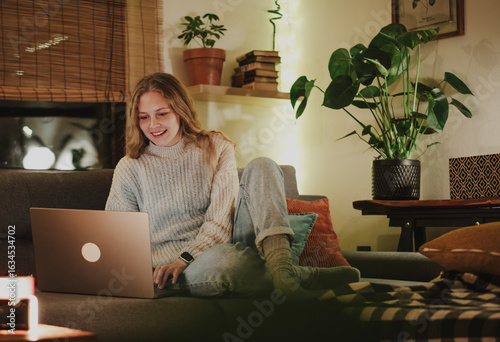Foto A young woman sitting comfortably on a couch using a laptop during a cozy and fe