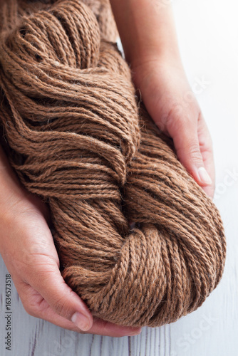 Hands of a Latina woman hold a ball of llama wool