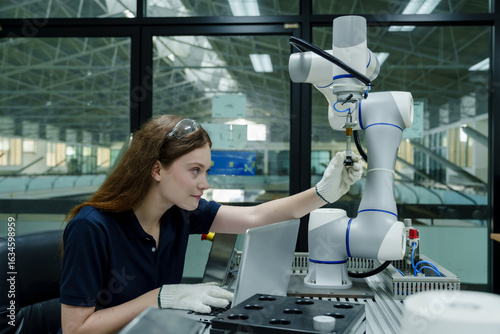 caucasian engineer woman interacting with robotic arm during real world training for automation and robotics in smart factory environment developing industry 4.0 workforce skills