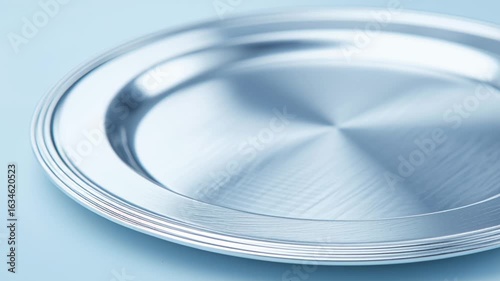 Shiny metal plate with smooth surface reflecting light and subtle blue background