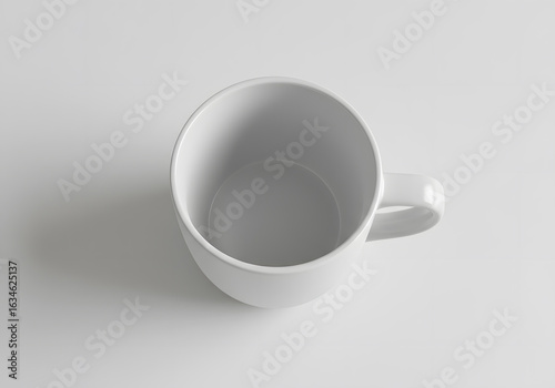 High angle view of an empty white ceramic mug on a light surface with soft shadows. Minimalist and clean kitchen concept.