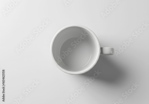 Top view of an empty white ceramic coffee mug on a white background with soft shadow. Minimalist design concept.